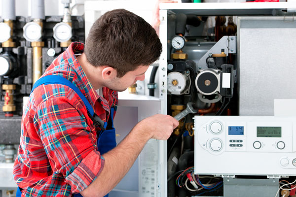 HVAC technician inspecting and repairing boiler controls in Brighton
