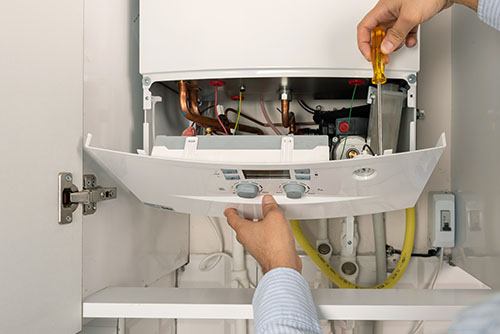 HVAC technician repairing an indoor boiler in Brighton