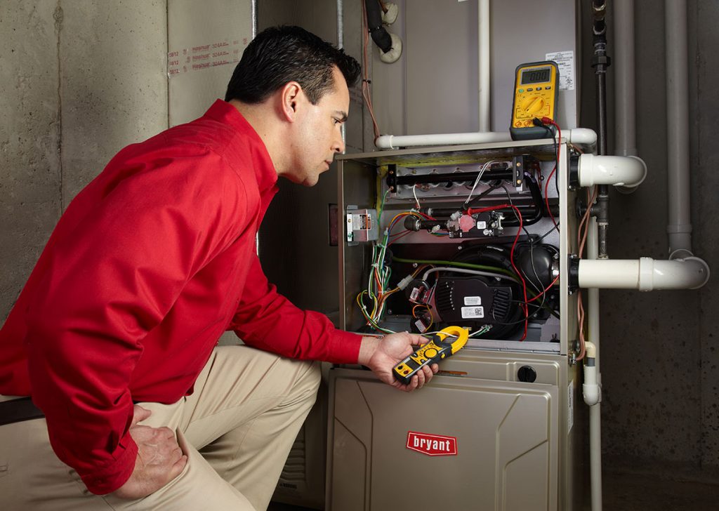 HVAC technician repairing an indoor furnace in Brighton