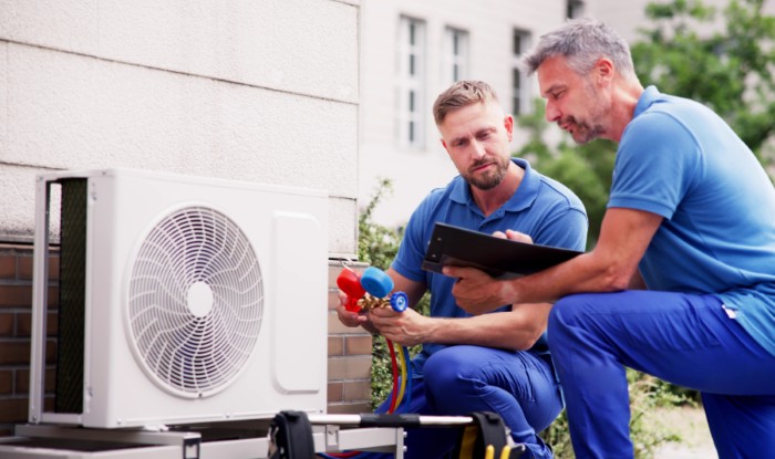 HVAC technicians installing an outdoor air conditioning unit in Brighton