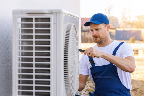 HVAC technician servicing an outdoor air conditioning unit in Brighton