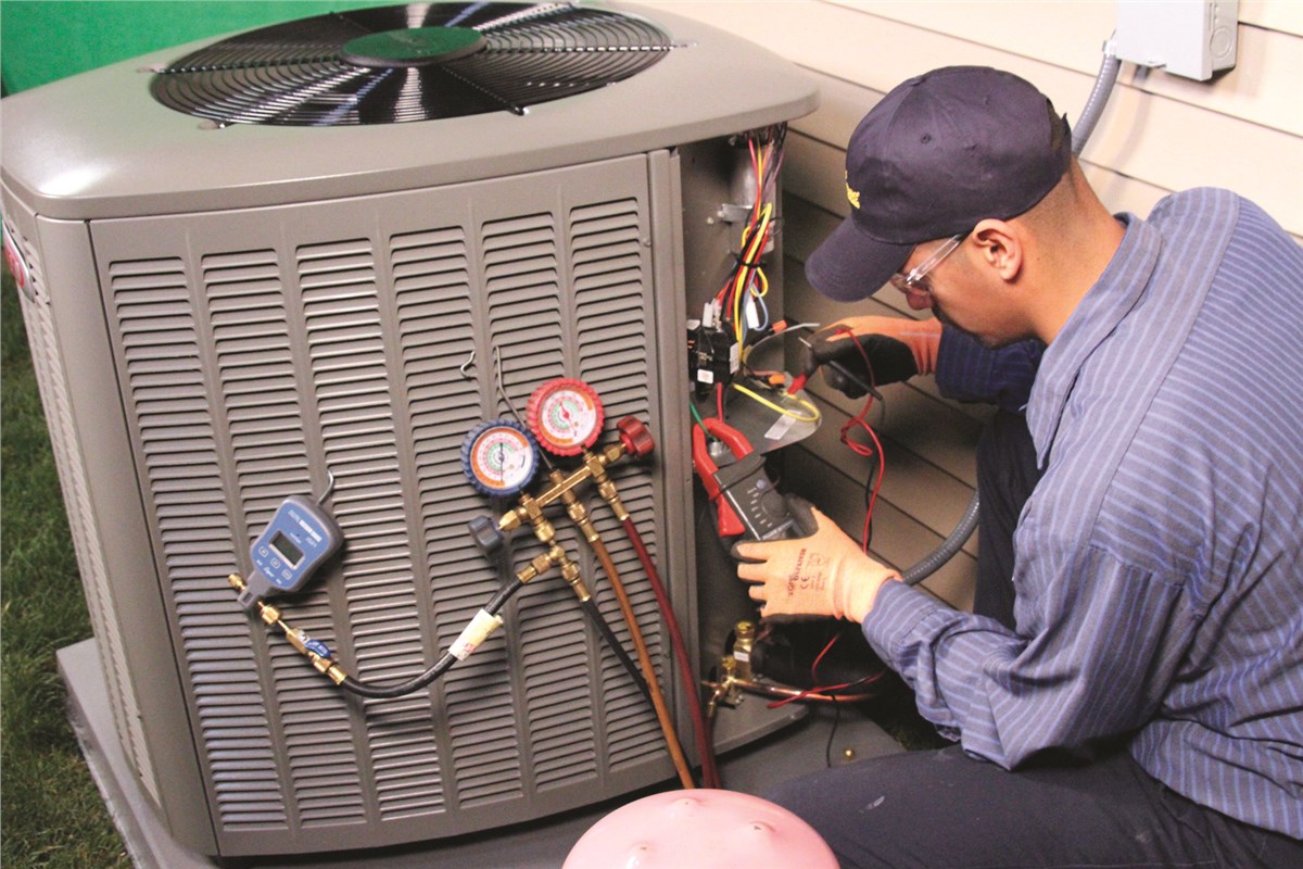 HVAC technician testing an outdoor air conditioning unit in Brighton