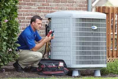 design-air-heating-and-air-conditioning-decatur-il-05 – Copy HVAC technician inspecting an outdoor air conditioning unit in Brighton, CO