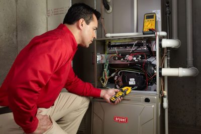 furnace repair Heating and air conditioning technician servicing an indoor furnace in Brighton, CO